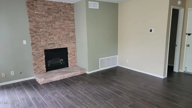 a view of empty room with wooden floor and fireplace