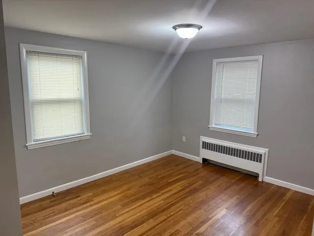 an empty room with wooden floor cabinet and windows