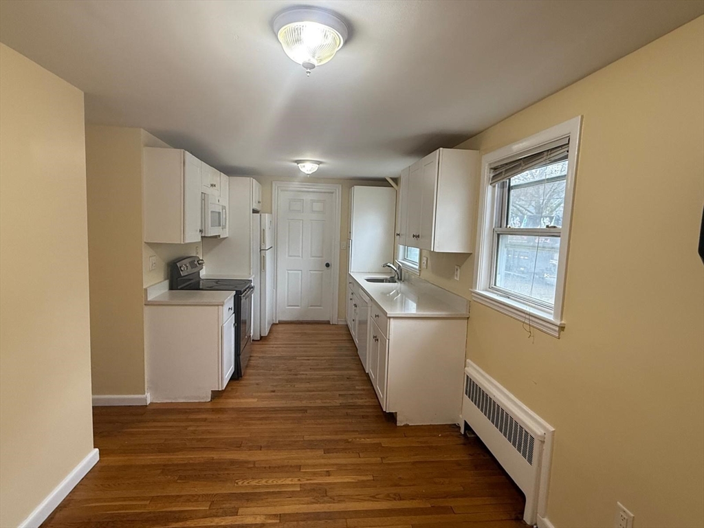39 Alpena Avenue Dedham, MA 02026 - Photo 9 of 11 a kitchen with refrigerator and white cabinets