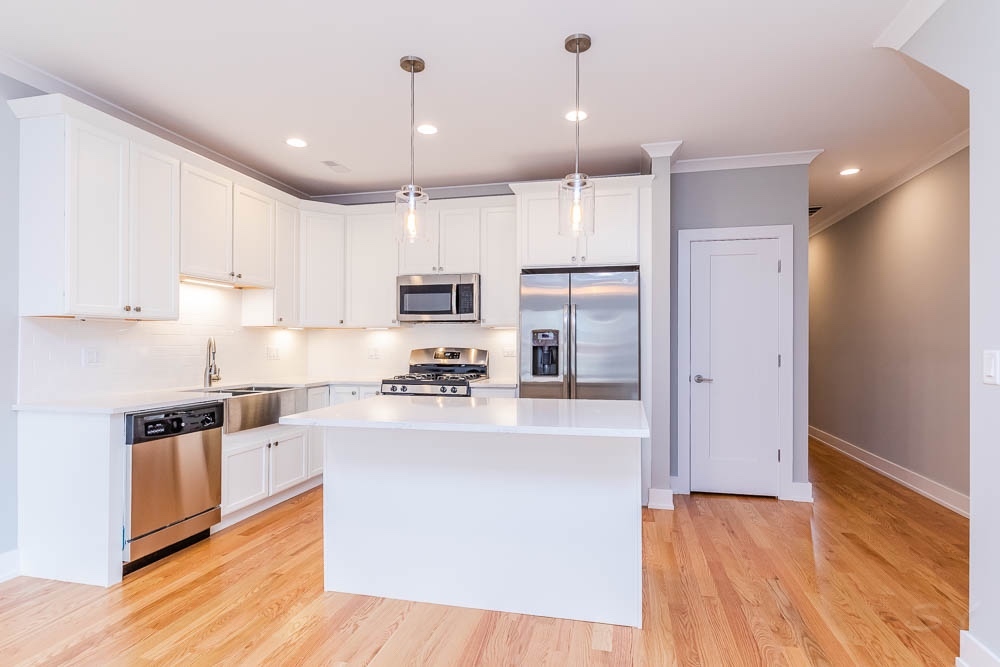 2307 West 19th Street, Unit 2 Chicago, IL 60608 - Photo 3 of 16 a large kitchen with stainless steel appliances granite countertop a refrigerator a stove a sink and white cabinets with wooden floor