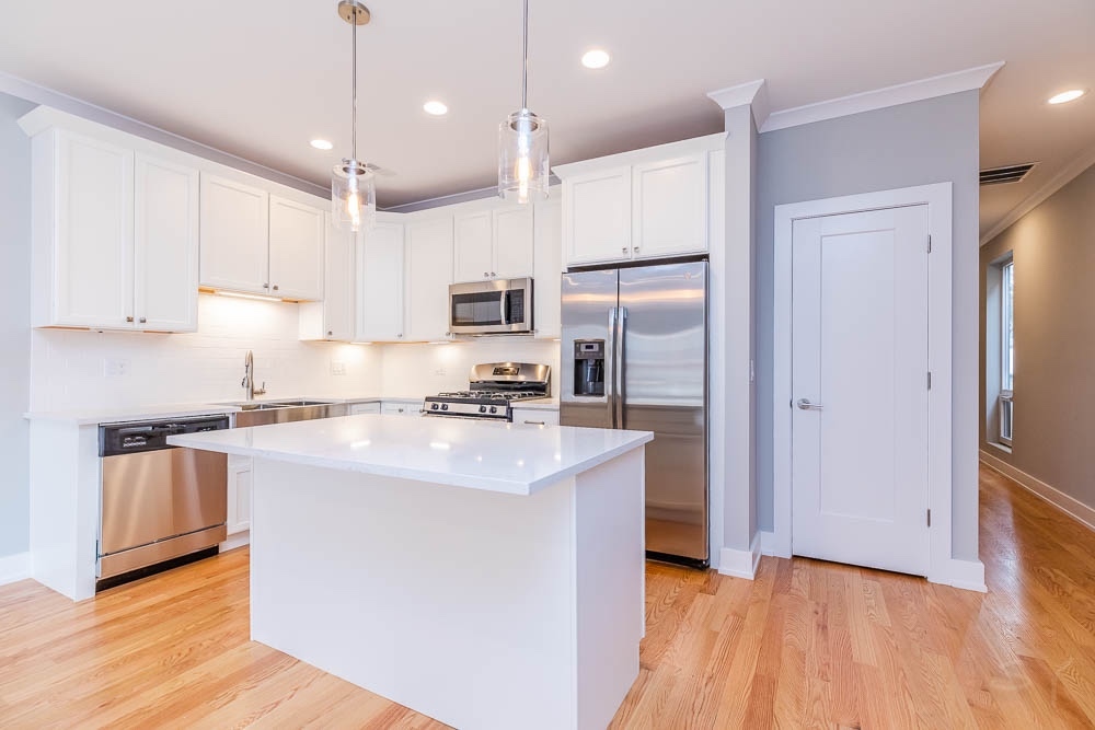 2307 West 19th Street, Unit 2 Chicago, IL 60608 - Photo 4 of 16 a kitchen with kitchen island a sink stainless steel appliances and cabinets