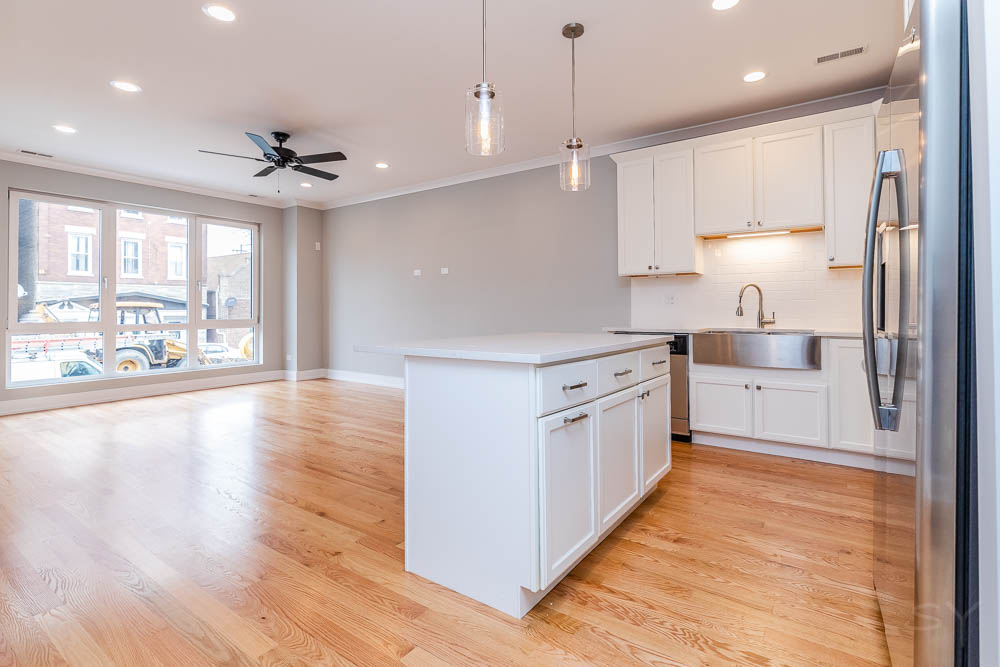 2307 West 19th Street, Unit 2 Chicago, IL 60608 - Photo 5 of 16 a large kitchen with stainless steel appliances a large counter top a stove a sink cabinets and a wooden floor