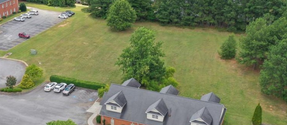 120 Perpetual Square Drive Anderson, SC 29621 - Photo 3 of 14 Aerial view showcasing a vast, verdant expanse with mature trees and ample parking next to a commercial building.