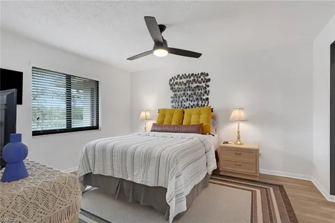 a bedroom with a bed and dresser with wooden floor