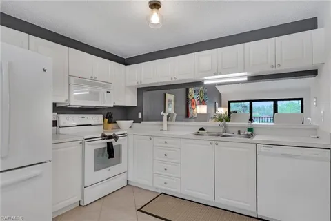 a kitchen with white cabinets and white appliances