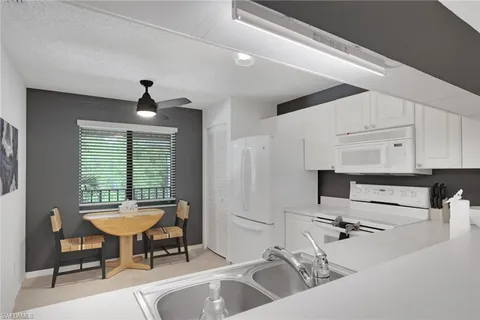 a view of a kitchen with kitchen island a sink stainless steel appliances and cabinets