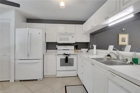 a kitchen with white cabinets and white appliances
