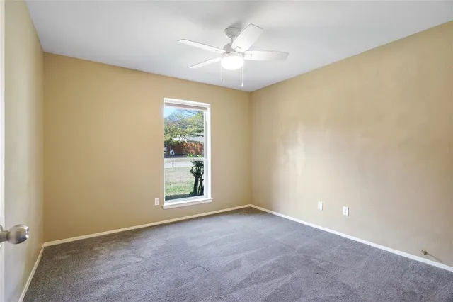 an empty room with windows and ceiling fan