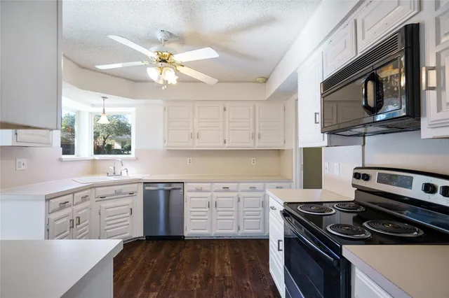 a kitchen with stainless steel appliances white cabinets granite counter tops and a sink