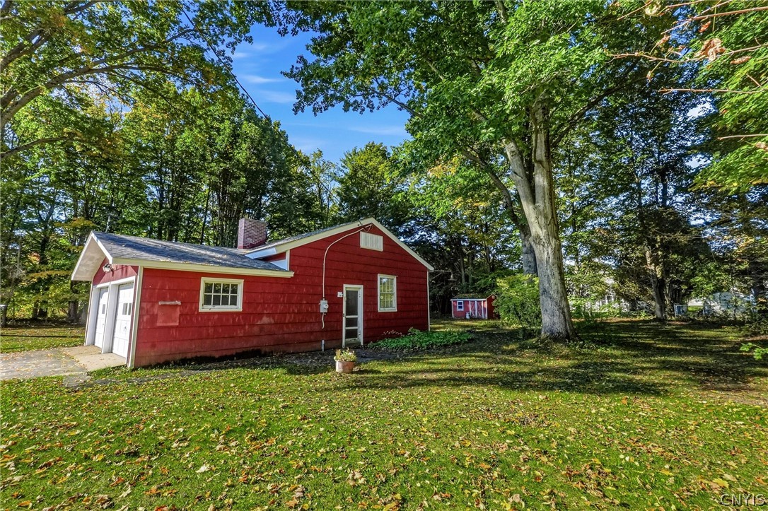 7779 Bell Road North Rome, NY 13440 - Photo 36 of 38 Mature trees shade a classic red-sided structure with an integrated garage on a grassy lot.