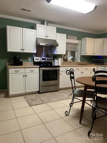 a kitchen with stainless steel appliances a stove a sink and white cabinets