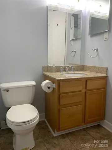 a bathroom with a granite countertop toilet sink and mirror