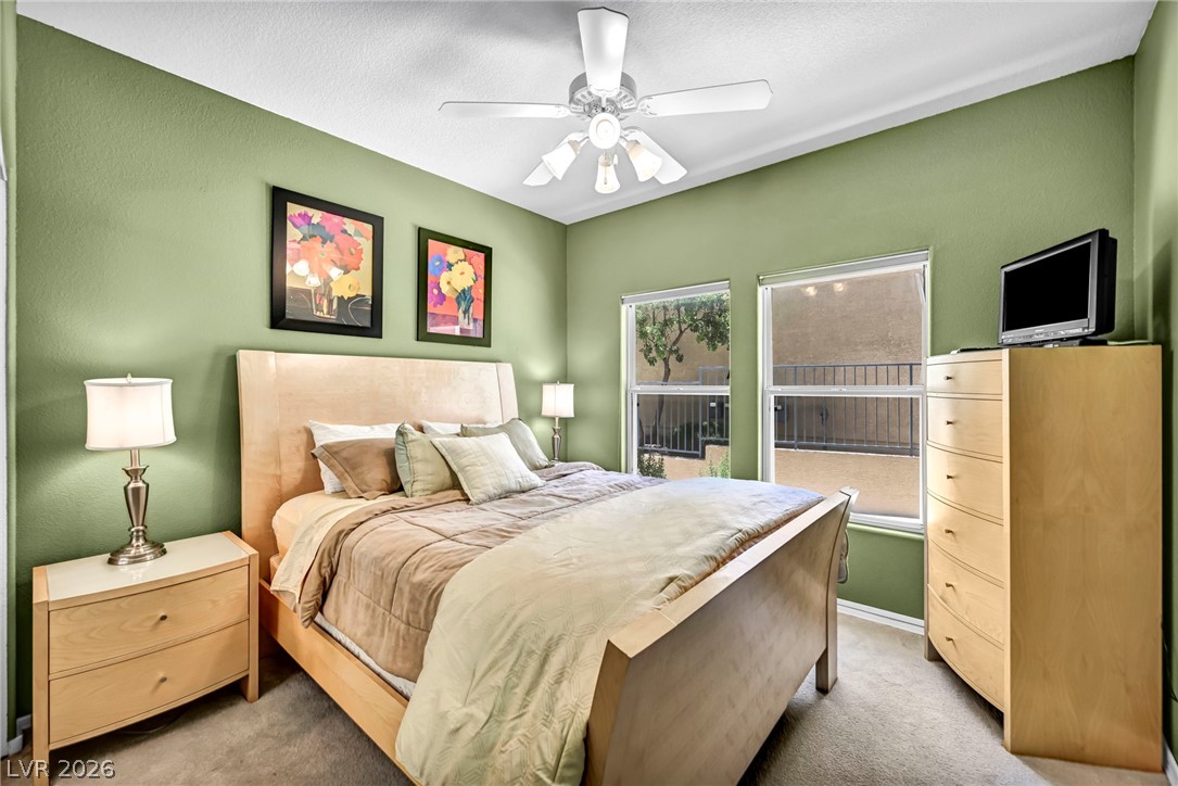 10730 Amber Ridge Drive, Unit 101 Las Vegas, NV 89144 - Photo 17 of 32 A well-lit primary bedroom features soft green walls and a ceiling fan for optimal comfort.