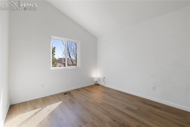 7827 Swiftrun Road Colorado Springs, CO 80920 - Photo 24 of 48 Spare room featuring visible vents, vaulted ceiling, baseboards, and wood finished floors