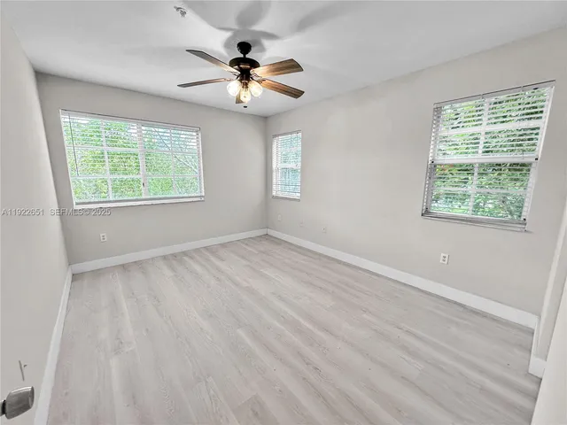a view of an empty room with a window and wooden floor