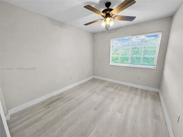 an empty room with a window and a fan