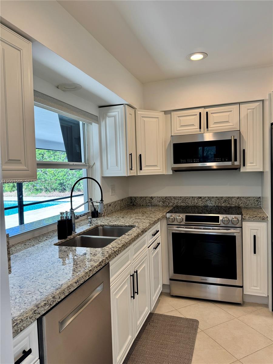 1093 Southwest 14th Street Boca Raton, FL 33486 - Photo 2 of 28 a kitchen with stainless steel appliances granite countertop a sink stove and microwave