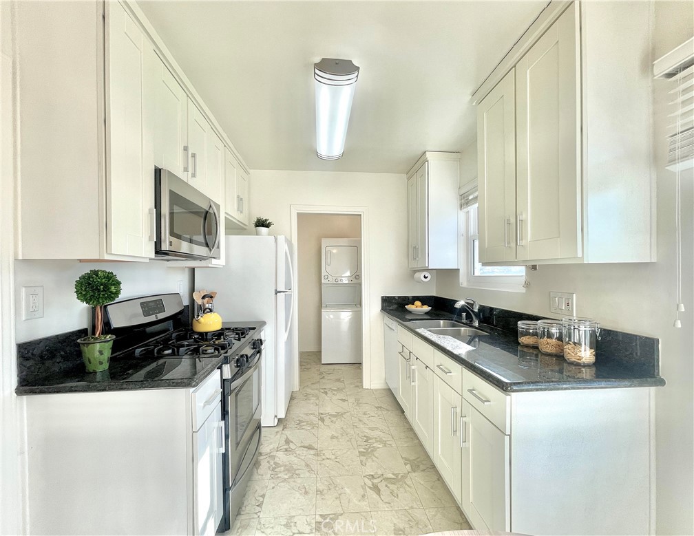a kitchen with stainless steel appliances a stove a sink a refrigerator and a cabinets