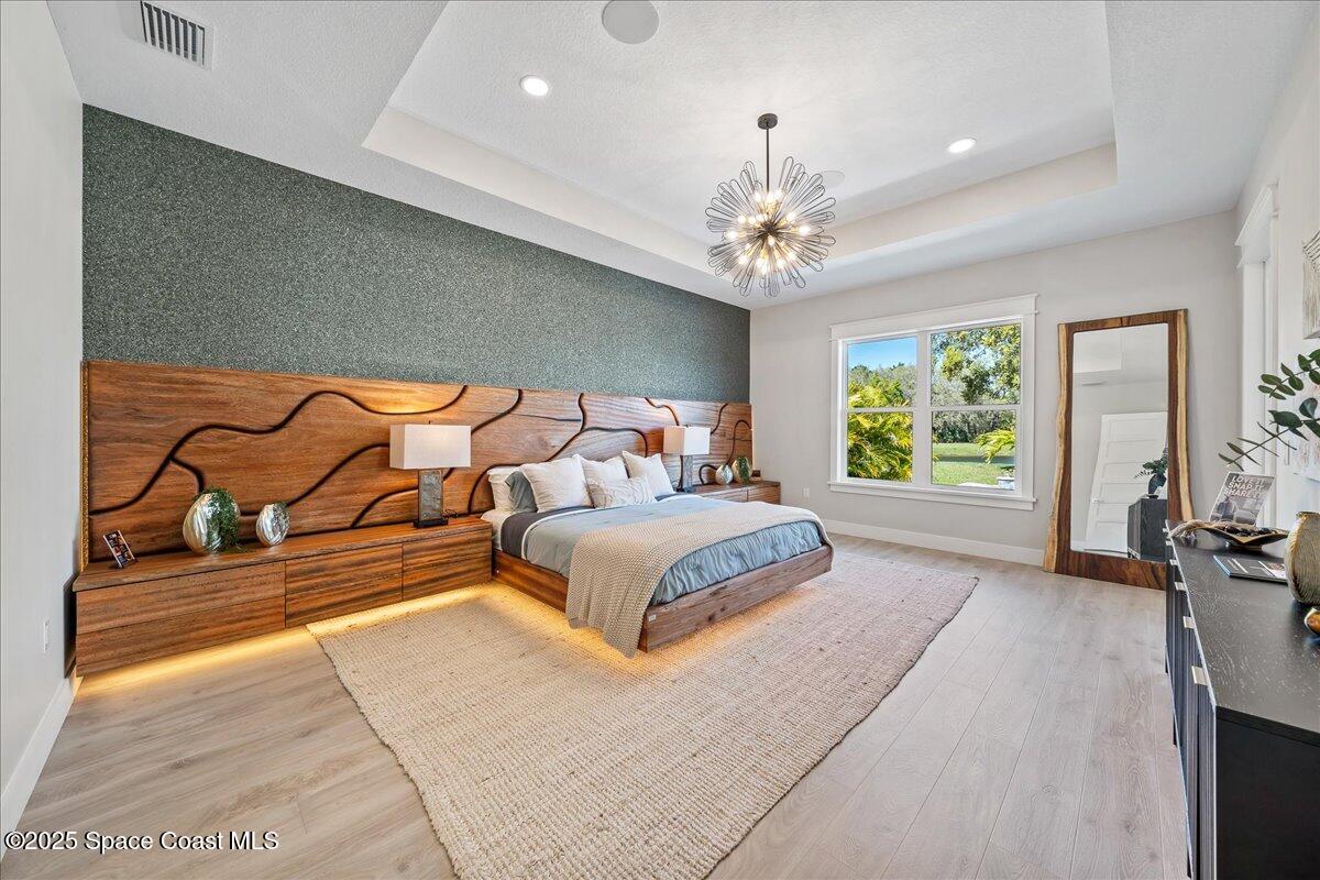 7953 Galikova Way Melbourne, FL 32940 - Photo 12 of 17 a spacious bedroom with a large bed and a chandelier