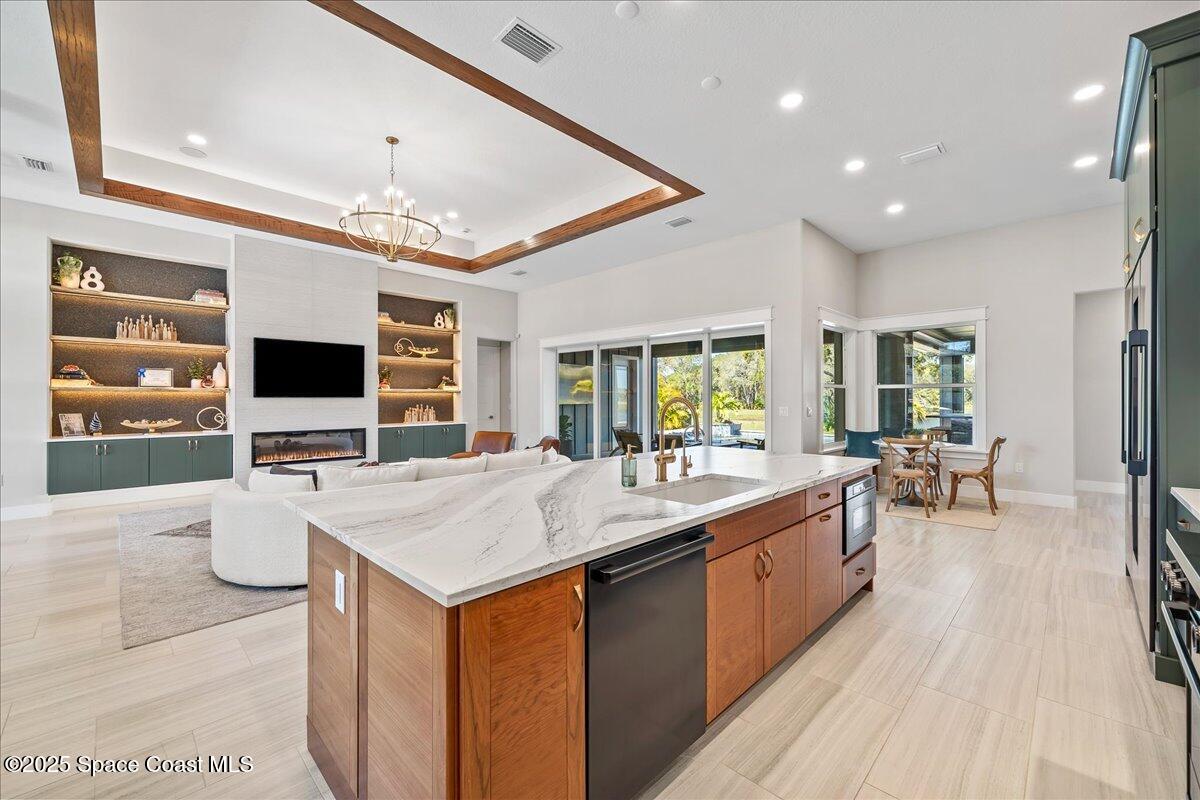 7953 Galikova Way Melbourne, FL 32940 - Photo 9 of 17 a large kitchen with stainless steel appliances kitchen island granite countertop a large stove a sink dishwasher and white cabinets with wooden floor
