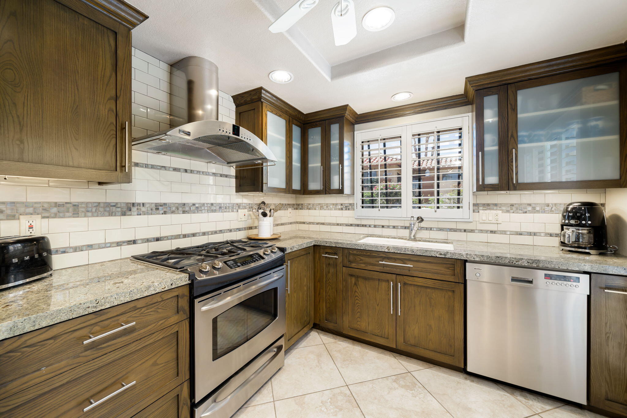 a kitchen with granite countertop stainless steel appliances a sink stove and cabinets
