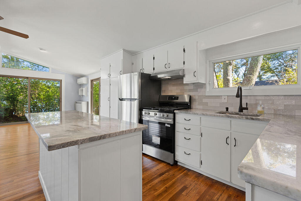 35 Santuit Lane Mashpee, MA 02649 - Photo 24 of 51 a kitchen with stainless steel appliances granite countertop a refrigerator a sink a stove a dining table and chairs with wooden floor