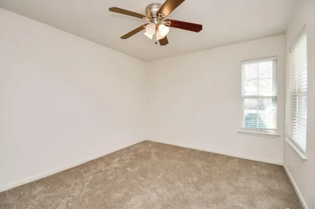 an empty room with chandelier fan and fireplace