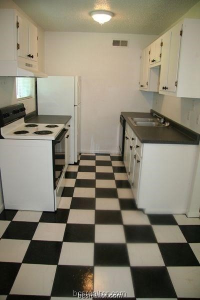 a kitchen with a checkered floor and white cabinets