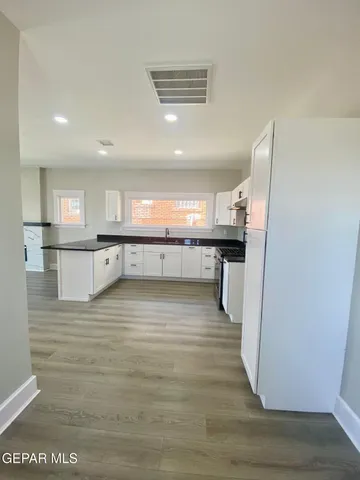 a view of a kitchen with kitchen island a sink wooden floor and stainless steel appliances