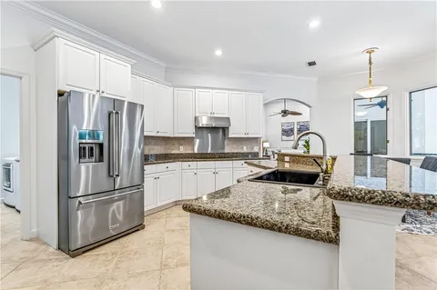 a kitchen with kitchen island granite countertop a refrigerator oven a sink and dishwasher