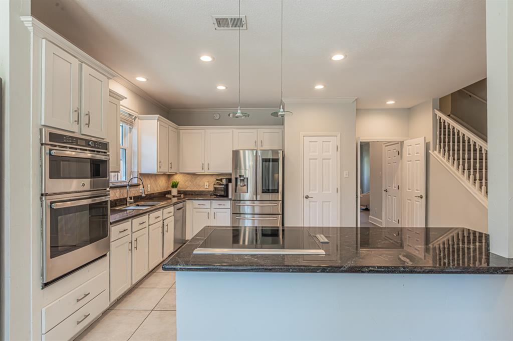 300 Sundance Circle Irving, TX 75063 - Photo 21 of 39 Kitchen featuring an island with a built-in cooktop, white cabinetry, stainless steel appliances, dark stone countertops, and recessed lighting