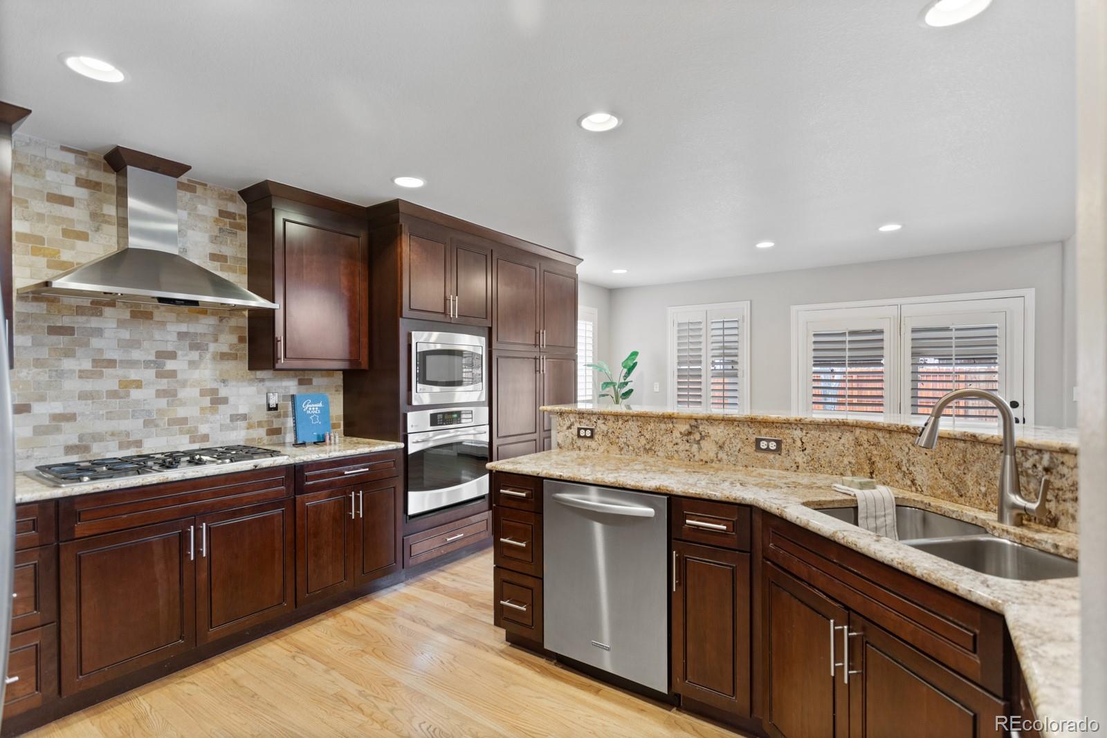 6681 Secrest Circle Arvada, CO 80007 - Photo 15 of 50 a kitchen with stainless steel appliances granite countertop a sink stove and cabinets