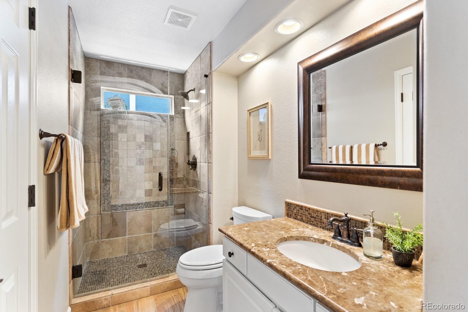 6681 Secrest Circle Arvada, CO 80007 - Photo 24 of 50 a bathroom with a granite countertop sink toilet and shower