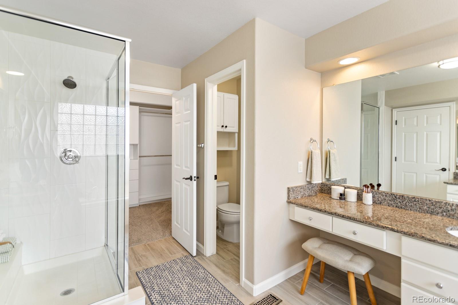 6681 Secrest Circle Arvada, CO 80007 - Photo 33 of 50 a bathroom with a granite countertop sink a mirror and a shower