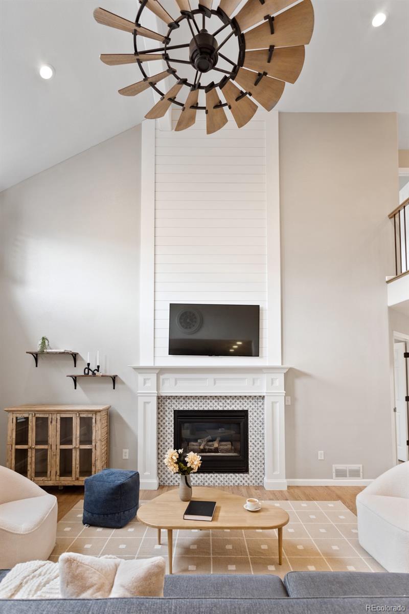 6681 Secrest Circle Arvada, CO 80007 - Photo 9 of 50 a living room with furniture a fireplace and a chandelier
