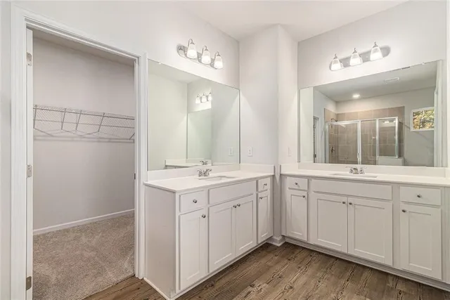 a spacious bathroom with a double vanity sink a mirror and a shower