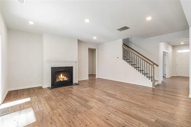 a view of an empty room with wooden floor fireplace and a window