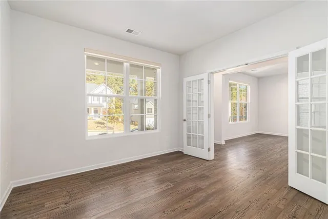 an empty room with wooden floor and windows