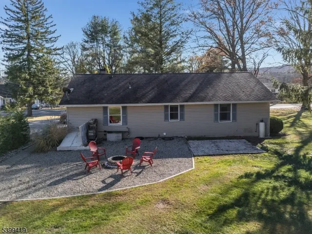 a view of a backyard with table and chairs under an umbrella with large trees
