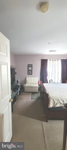 a bedroom with a bed a flat screen tv and a window