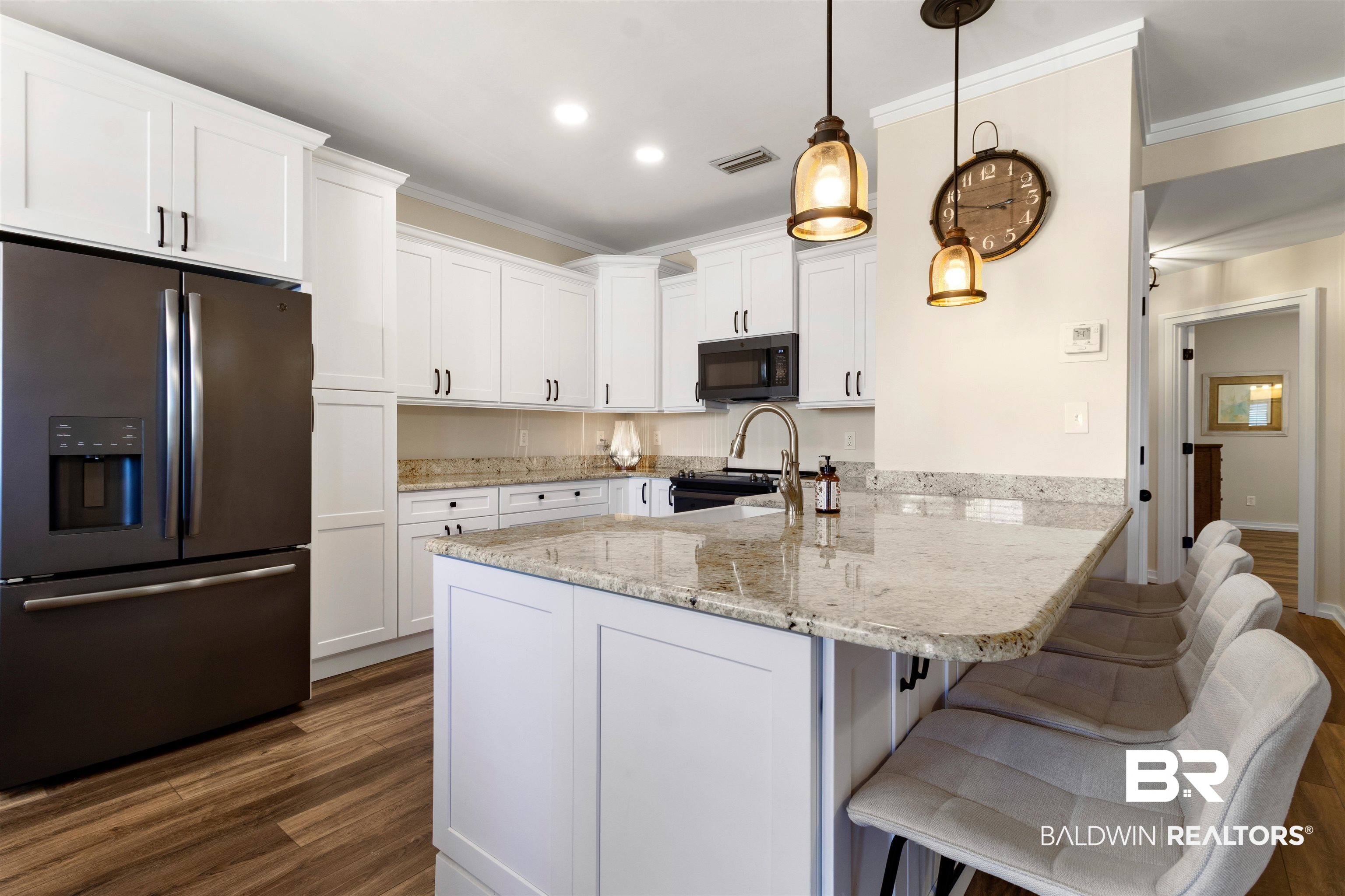 3543 Bayou Road, Unit 5 Orange Beach, AL 36561 - Photo 8 of 33 Modern kitchen featuring white shaker cabinetry, granite countertops, wood-finish flooring, and a central island with bar seating