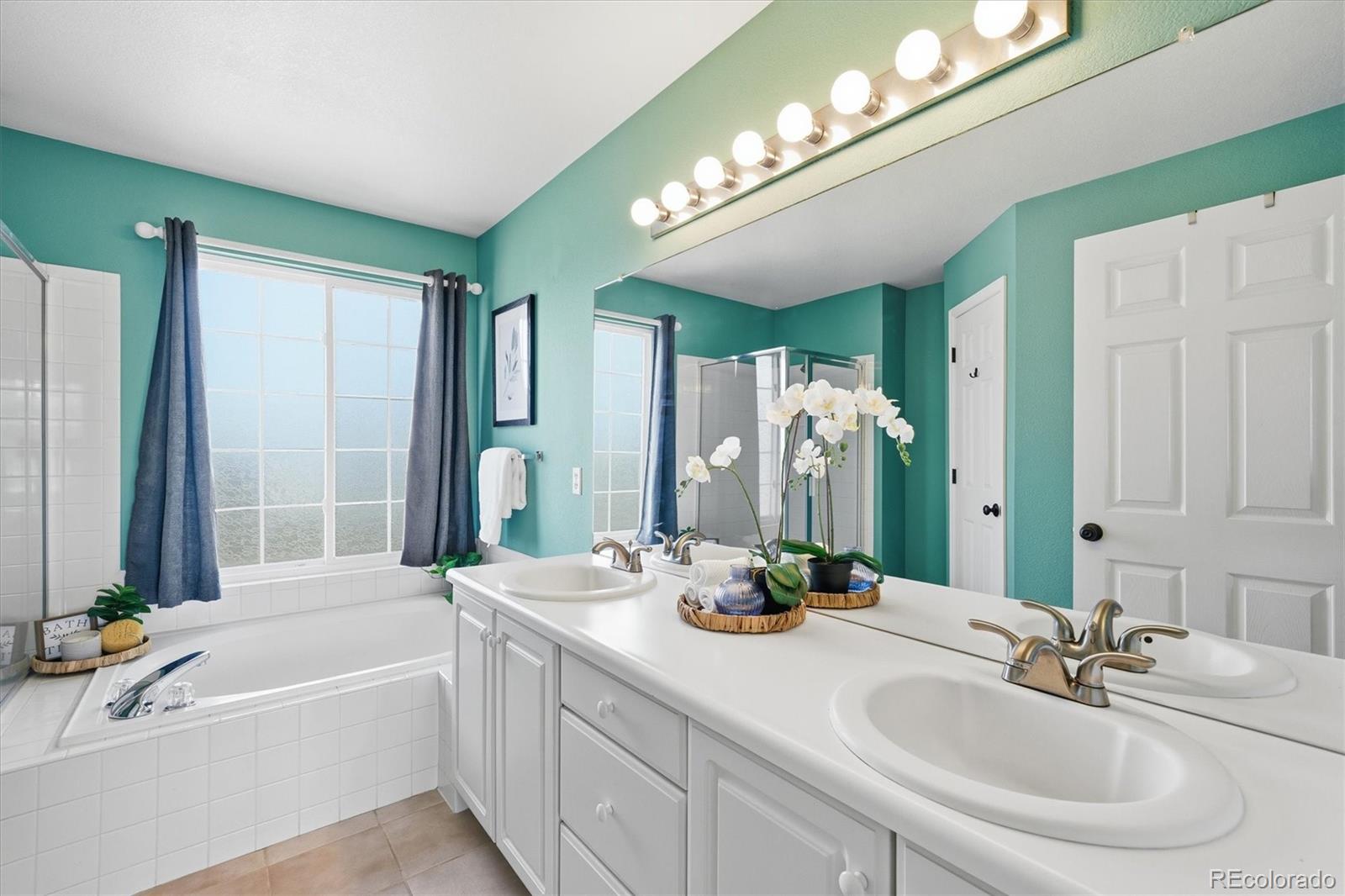 9629 Burberry Way Highlands Ranch, CO 80129 - Photo 27 of 50 a bathroom with a bathtub a double vanity sink and a mirror