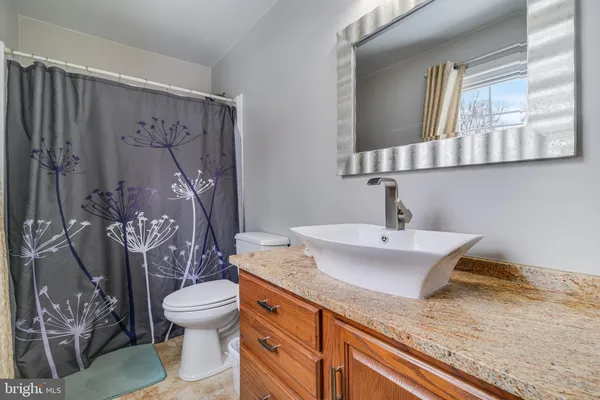 a bathroom with a granite countertop sink mirror vanity and toilet