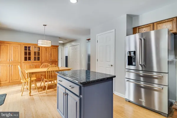 a kitchen with stainless steel appliances granite countertop a refrigerator a stove and a dining table with wooden floors