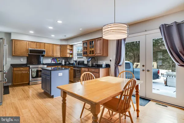 a kitchen with stainless steel appliances granite countertop a stove top oven a sink a dining table and chairs