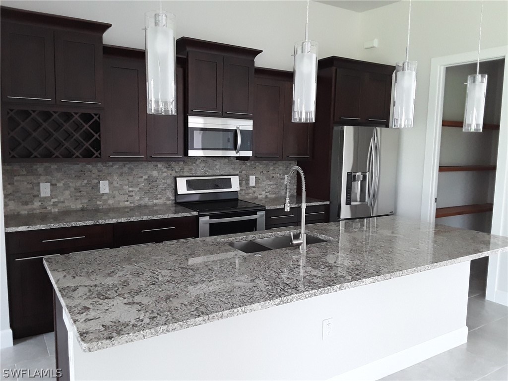 478 Rajah Street Lehigh Acres, FL 33974 - Photo 5 of 13 a kitchen with stainless steel appliances granite countertop a sink refrigerator and microwave