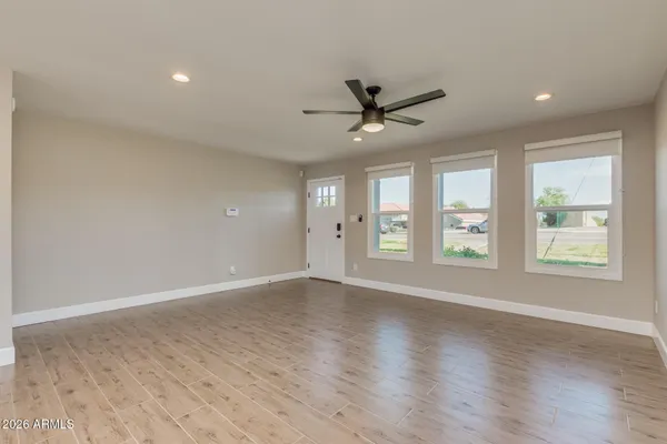 a view of an empty room with a window and wooden floor