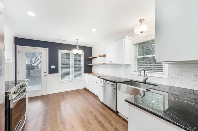 a large kitchen with granite countertop a large window and stainless steel appliances