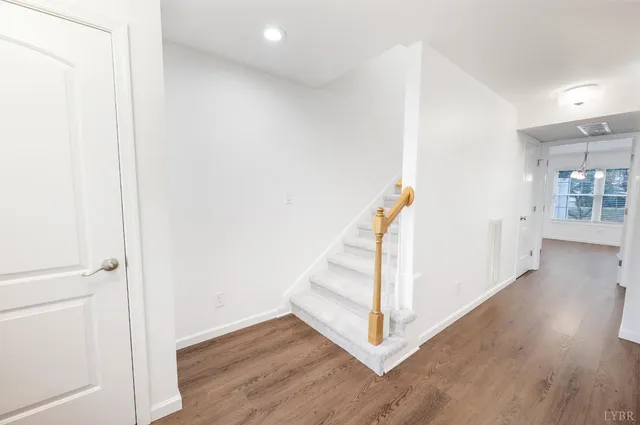 a view of a hallway with wooden floor and stairs