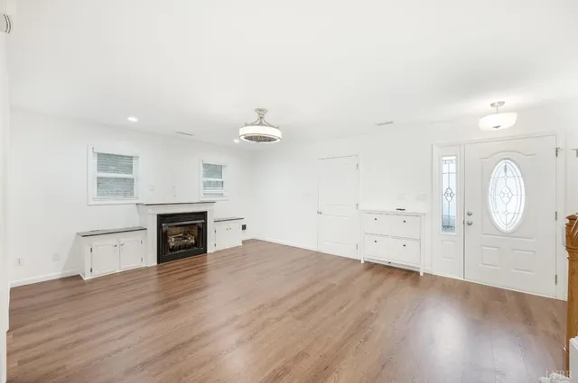 an empty room with wooden floor cabinet and a window